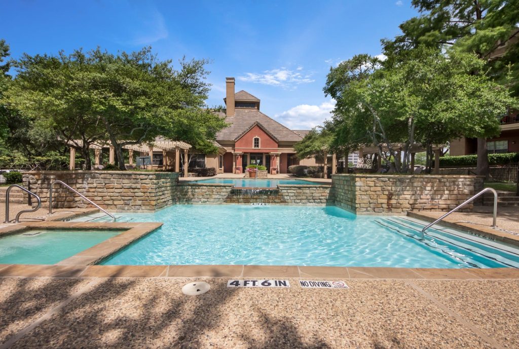 A beautiful tiered outdoor swimming pool and hot tub area with stone walls and a fountain in Jefferson, Texas, showcasing a relaxing getaway spot just a short drive from Gilmer.